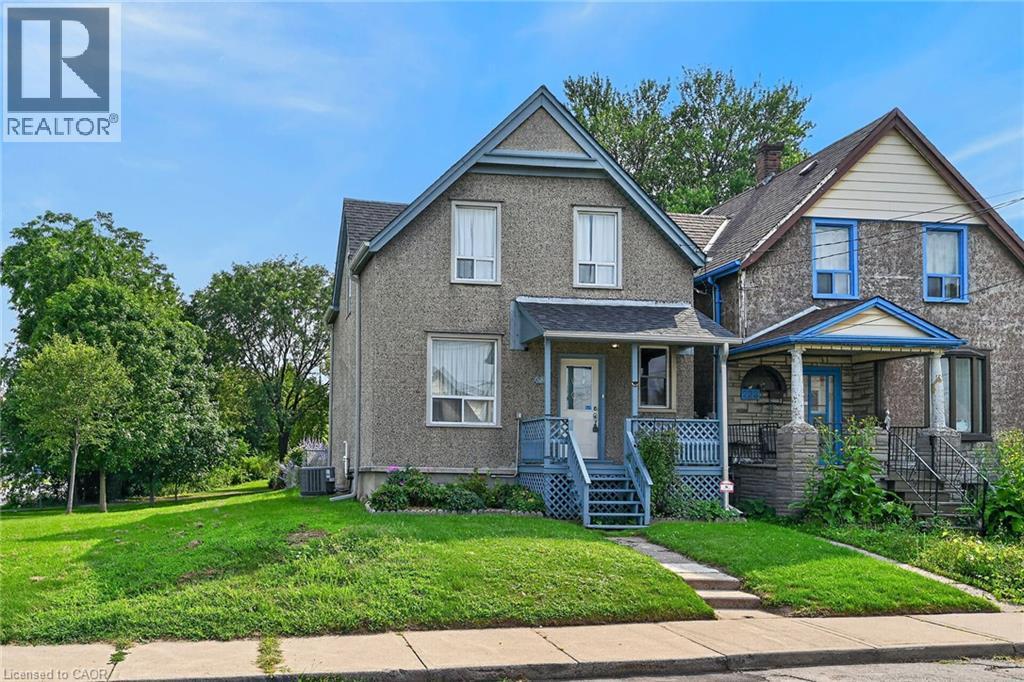 Two-story residence with a covered front porch featuring a lattice railing, a peaked gable roof, and a paved walkway leading to the entrance - 230 Picton Street E, Hamilton, ON - Outdoor With Facade
