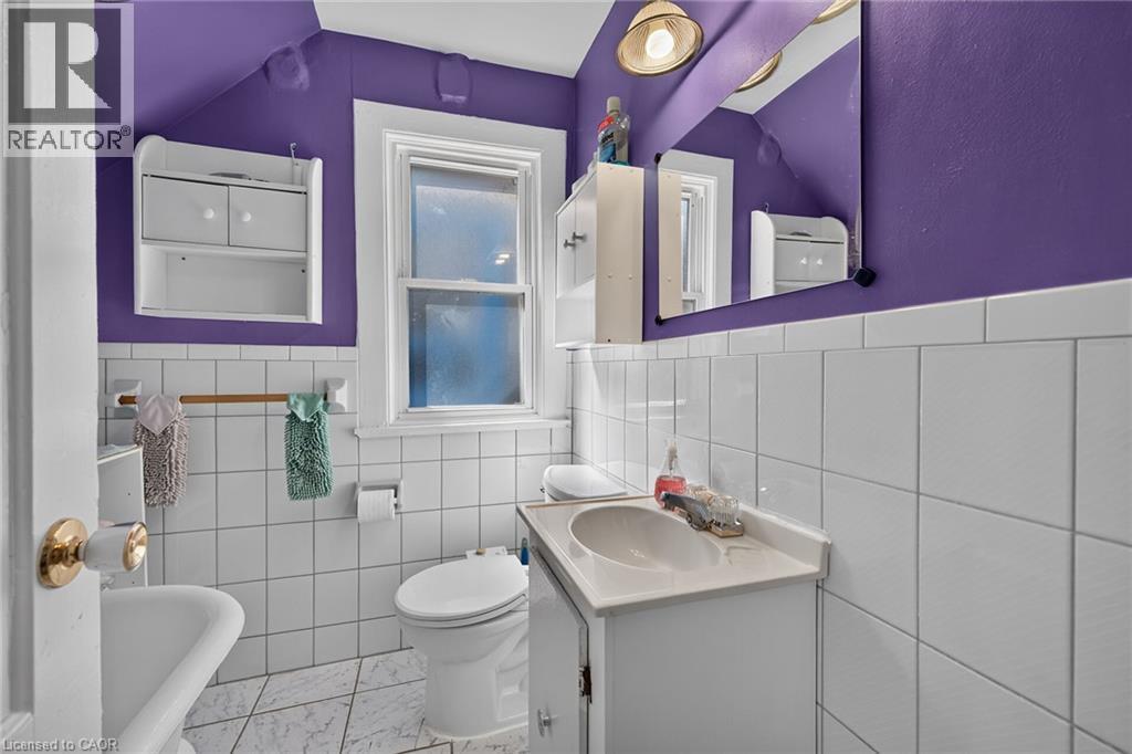 Bathroom featuring white wall tiling, vanity with integrated sink, wall-mounted mirror, and a window - 230 Picton Street E, Hamilton, ON - Indoor Photo Showing Bathroom