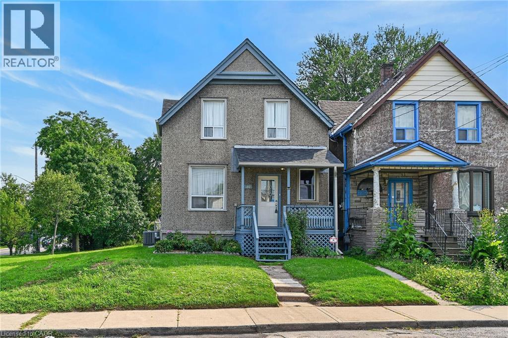 Exterior featuring a gabled roofline, light-colored stucco finish, covered front porch, and a dedicated walkway - 230 Picton Street E, Hamilton, ON - Outdoor With Facade