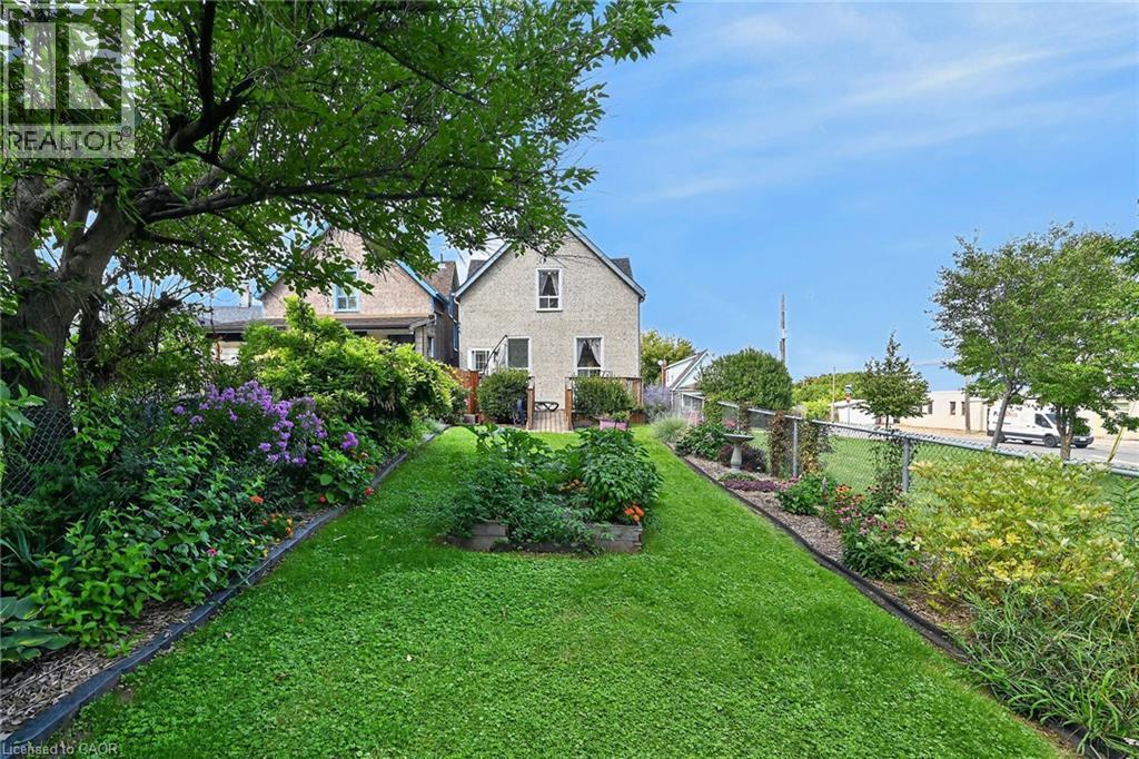 Expansive backyard featuring a manicured lawn, established garden beds, and mature trees - 230 Picton Street E, Hamilton, ON - Outdoor