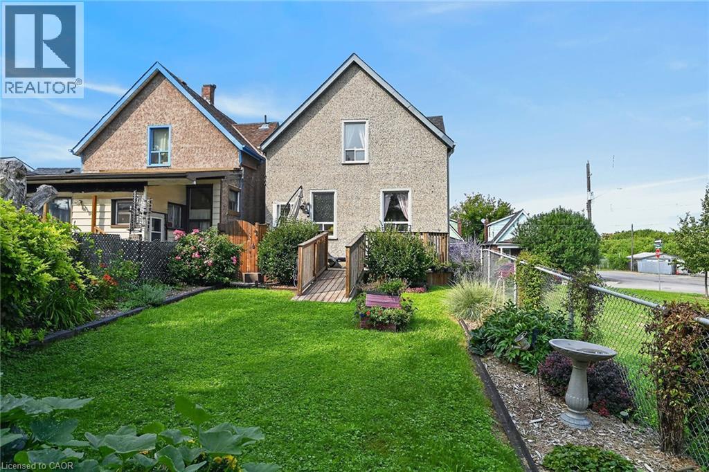 Manicured lawn with established garden beds, bordered by a chain-link fence - 230 Picton Street E, Hamilton, ON - Outdoor With Deck Patio Veranda