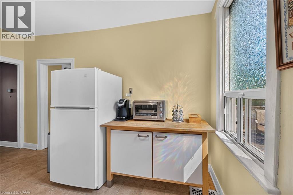 White two-door refrigerator, wood-finish countertop, white base cabinetry with brushed nickel hardware, and a window with textured glass - 230 Picton Street E, Hamilton, ON - Indoor