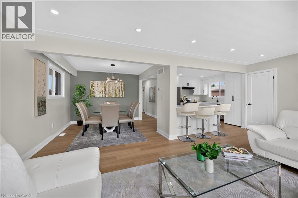 Open-concept living area featuring warm wood-finish flooring throughout, recessed ceiling lighting, and a gray accent wall - 40 Purdy Crescent, Hamilton, ON - Indoor Photo Showing Living Room