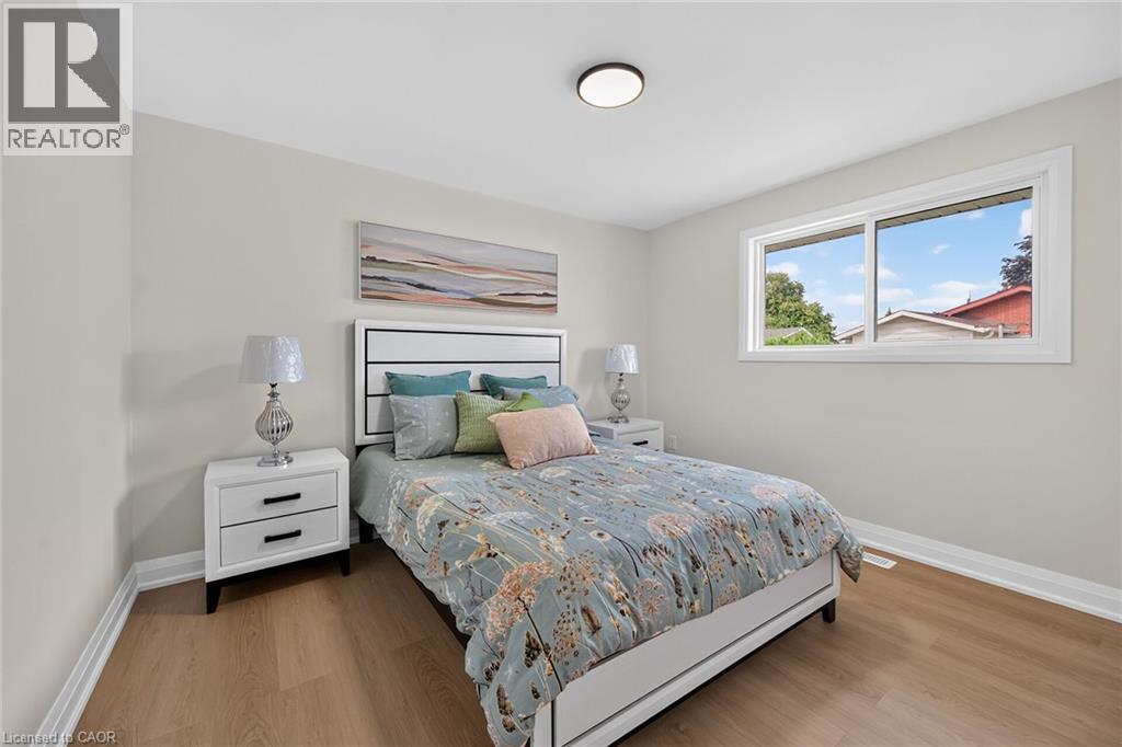 Wood-finish flooring with white baseboards, light neutral wall paint, and a white framed window - 40 Purdy Crescent, Hamilton, ON - Indoor Photo Showing Bedroom