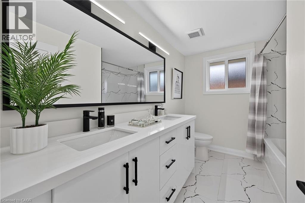 Dual vanity with integrated sinks and matte black fixtures, set against a large framed mirror with linear lighting - 40 Purdy Crescent, Hamilton, ON - Indoor Photo Showing Bathroom