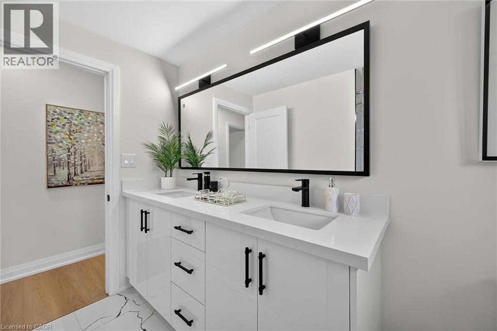Dual vanity with integrated rectangular sinks, white countertops, black-framed mirror, and black wall-mounted lighting - 40 Purdy Crescent, Hamilton, ON - Indoor Photo Showing Bathroom