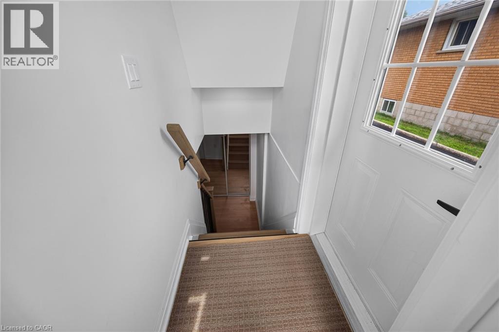 Stairwell with carpeted steps, a light wood handrail, and white paneled door with glass inserts - 40 Purdy Crescent, Hamilton, ON - Indoor Photo Showing Other Room