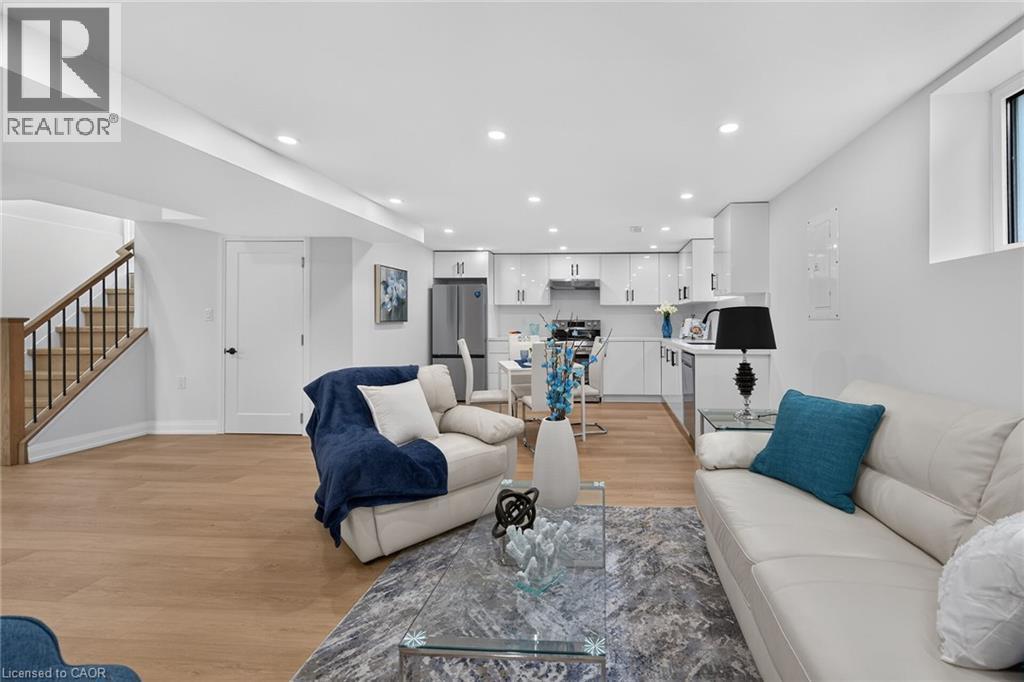Open-concept living space featuring wood-finish flooring, recessed lighting, and a white kitchen with high-gloss cabinetry and stainless steel appliances - 40 Purdy Crescent, Hamilton, ON - Indoor Photo Showing Living Room
