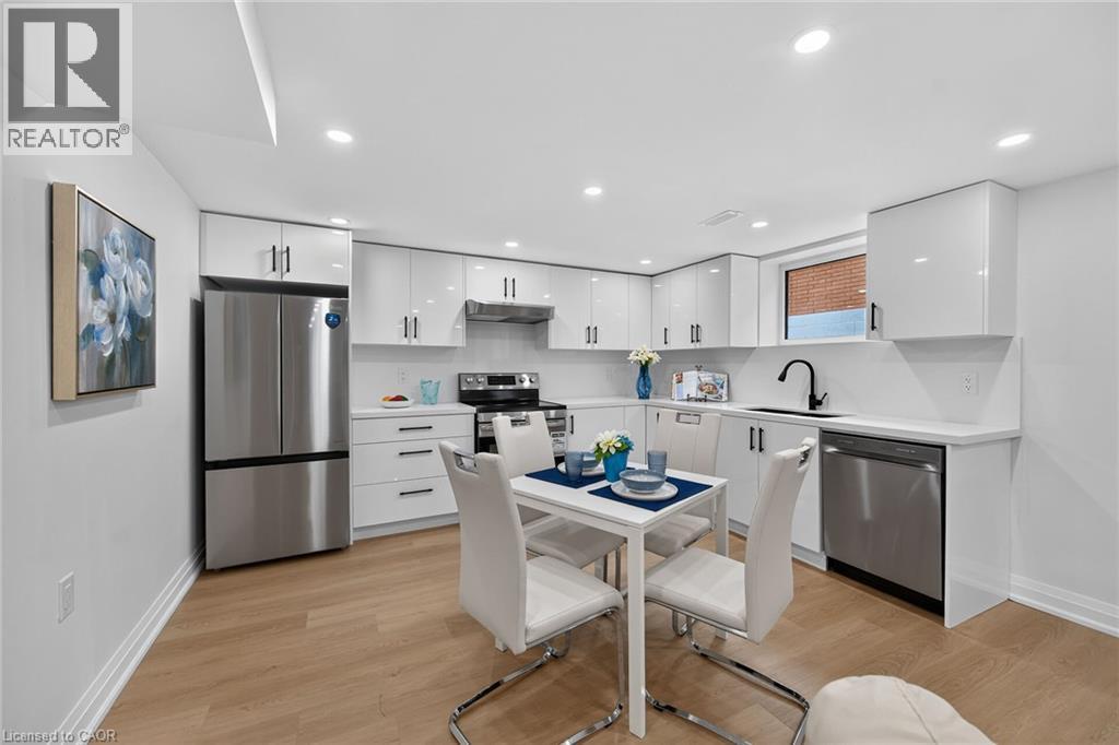 White cabinetry with dark hardware, stainless steel appliances, wood-finish flooring, recessed lighting, and a black gooseneck faucet - 40 Purdy Crescent, Hamilton, ON - Indoor Photo Showing Kitchen