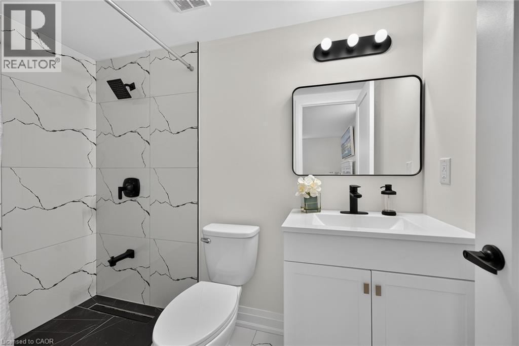 Modern bathroom featuring a single vanity with storage, a rectangular mirror, and a wall-mounted light fixture - 40 Purdy Crescent, Hamilton, ON - Indoor Photo Showing Bathroom