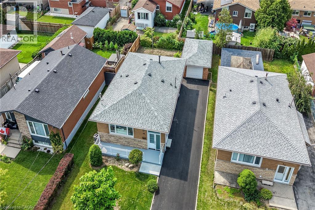 Property featuring a light gray shingle roof, stone and brick exterior, extended paved driveway, front porch, and a detached garage - 40 Purdy Crescent, Hamilton, ON - Outdoor