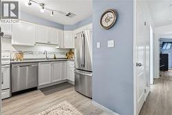 Kitchen featuring white cabinetry, stainless steel appliances, a tile backsplash, track lighting, and wood-finish flooring -