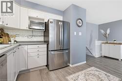 Modern kitchen featuring white cabinetry, stainless steel refrigerator, and wood-finish flooring -