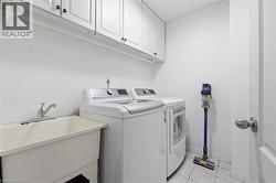 White cabinetry with black hardware, utility sink with chrome faucet, and tiled flooring -