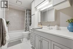 Bathroom featuring a white bathtub, ceramic wall tiling with accent border, and a vanity with a surface-mounted sink -