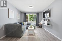 Recessed ceiling lighting, light gray wall paint, wood-finish flooring, white window trim, built-in shelving -