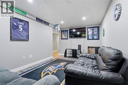 Finished basement recreation room featuring plush black leather seating, branded sports memorabilia displays, recessed ceiling lighting, carpeted flooring with coordinating area rug, wall-mounted flat -
