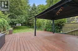 Expansive wood-finish deck with a built-in gazebo featuring an overhead light fixture -