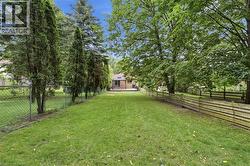 Expansive backyard with a manicured lawn, established trees, and a wooden privacy fence -