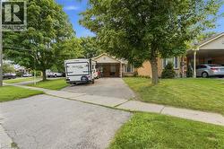 Brick exterior residence with an attached carport, mature trees, and a concrete driveway -
