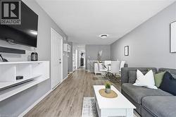 Open-concept living area with wood-finish flooring, neutral gray wall tones, and recessed ceiling lighting -