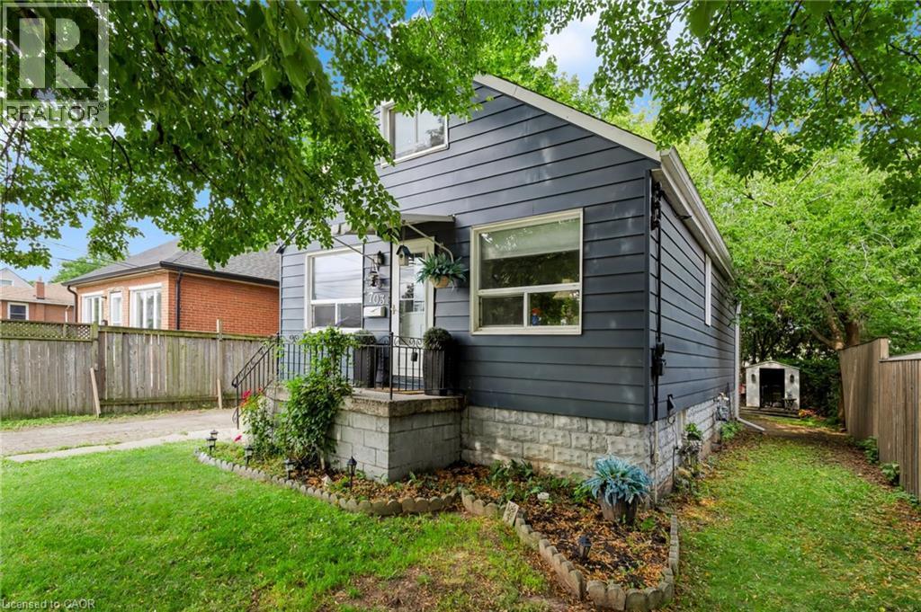 Siding exterior with a covered front porch, concrete porch foundation, and a detached shed - 703 Brighton Avenue, Hamilton, ON - Outdoor