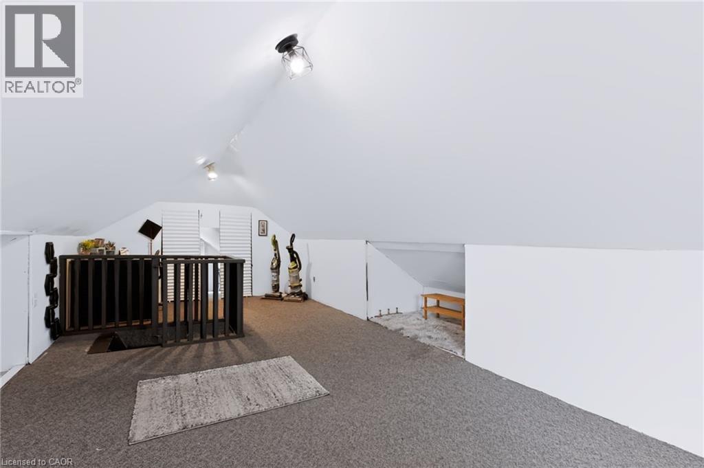 Sloped ceiling attic space featuring track lighting, built-in louvered doors, and a partial wall separation - 703 Brighton Avenue, Hamilton, ON - Photo Showing Other Room