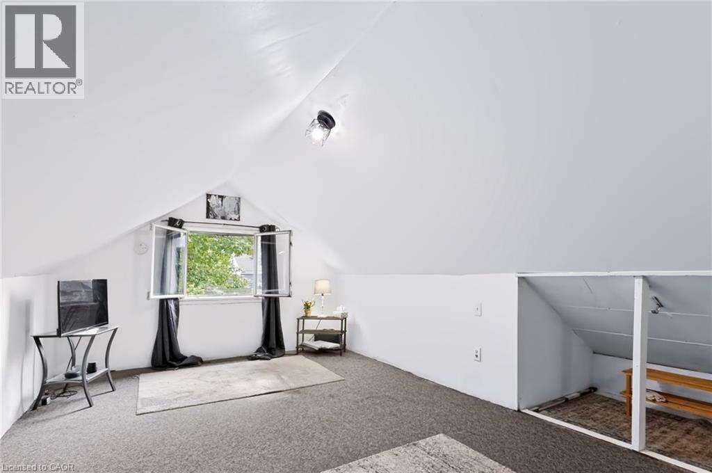 Sloped ceilings with recessed lighting, carpet flooring, and a large casement window - 703 Brighton Avenue, Hamilton, ON - Indoor