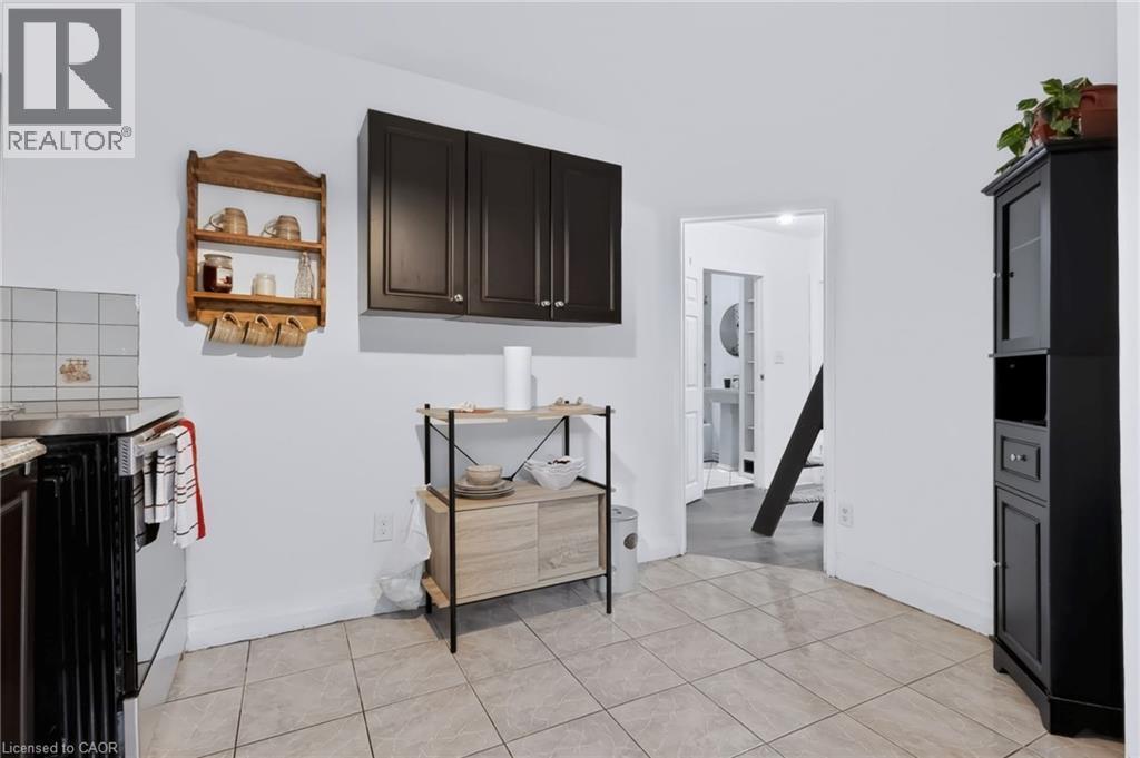 White walls with dark-finish upper cabinetry and light-toned tile flooring - 703 Brighton Avenue, Hamilton, ON -