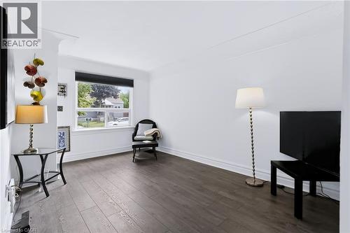 Wood-finish flooring, white walls, and a large window with a roller shade - 703 Brighton Avenue, Hamilton, ON 