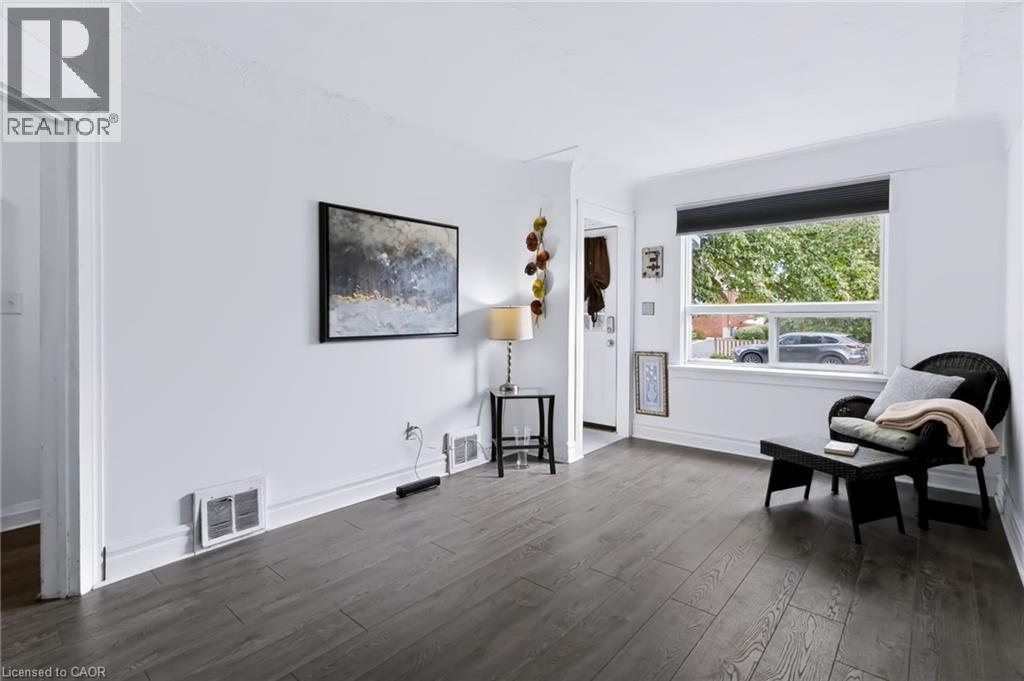 Wood-finish flooring, white painted walls, large window with roller shade, and white trim - 703 Brighton Avenue, Hamilton, ON