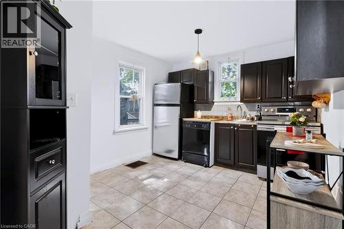 Kitchen featuring dark wood-finish cabinetry, stainless steel appliances, and tiled flooring - 703 Brighton Avenue, Hamilton, ON 