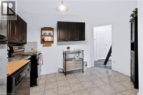 Kitchen featuring dark cabinetry, tile flooring, a built-in dishwasher, and a paneled door - 703 Brighton Avenue, Hamilton, ON 