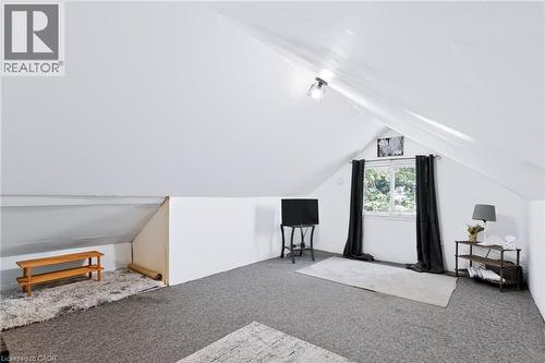 Attic space with sloped ceilings, a centered window, and a wall-mounted light fixture - 703 Brighton Avenue, Hamilton, ON 