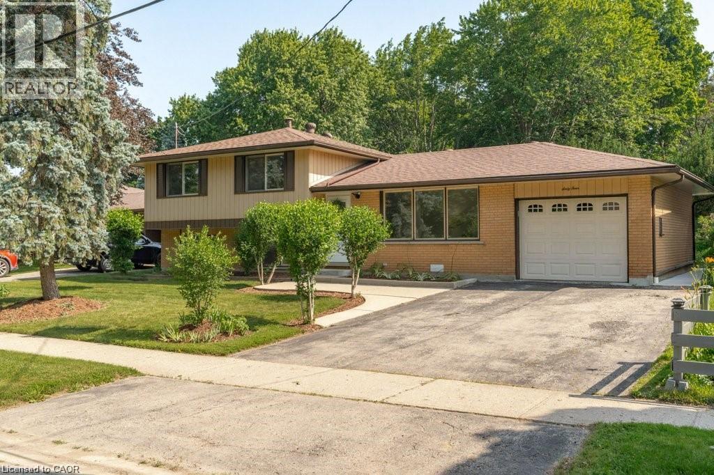 Split-level residence featuring brick and siding exterior, attached garage, paved driveway, and established front landscaping - 64 Warren Road, Kitchener, ON - Outdoor