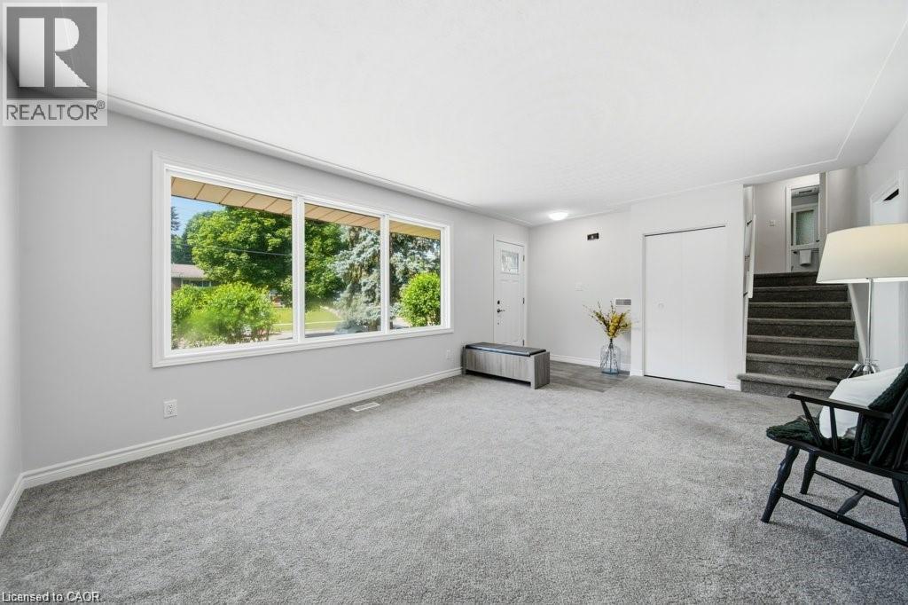 Expansive window wall, grey carpet flooring, white walls, white trim, and a built-in closet with bi-fold doors - 64 Warren Road, Kitchener, ON - Indoor Photo Showing Other Room