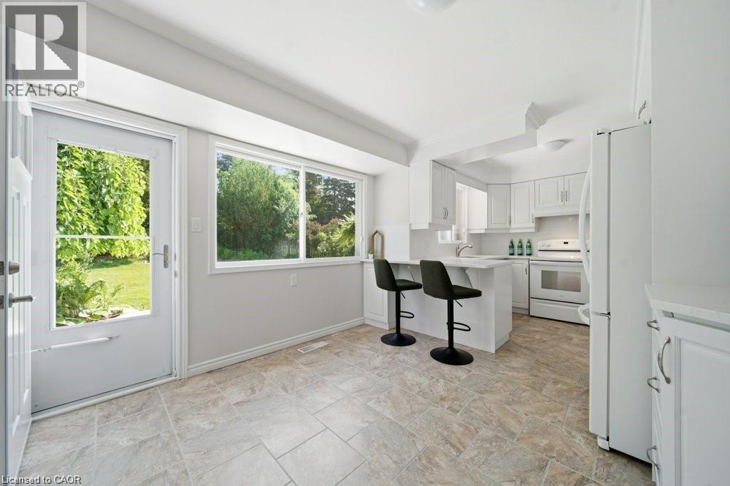 Kitchen featuring white cabinetry, white appliances, a built-in breakfast bar, and tile flooring - 64 Warren Road, Kitchener, ON - Indoor Photo Showing Kitchen