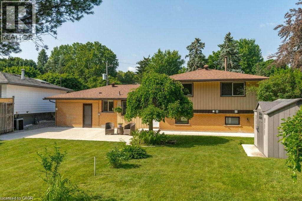 Expansive lawn area with a concrete patio and a detached storage shed - 64 Warren Road, Kitchener, ON - Outdoor