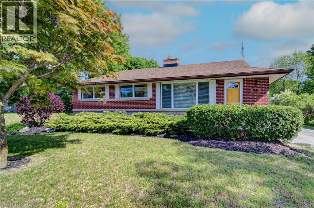 Brick exterior with a brown shingle roof, complemented by a yellow entry door and white window trim - 251 Union Street E, Waterloo, ON - Outdoor