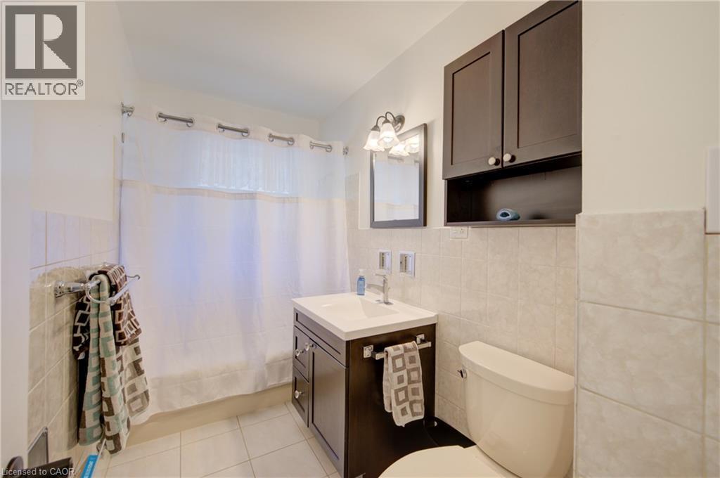 Dark wood-finish vanity with an integrated sink, polished chrome faucet, and mirrored medicine cabinet - 251 Union Street E, Waterloo, ON - Indoor Photo Showing Bathroom