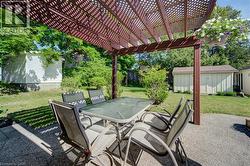 Expansive patio featuring a wooden pergola, concrete surfacing, and a visible storage shed -