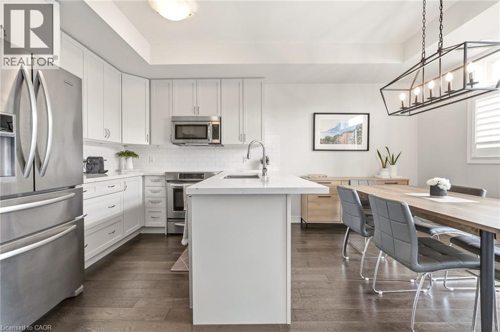 Modern kitchen and dining area featuring white shaker cabinetry, stainless steel appliances including French-door refrigerator and gas range, white quartz waterfall island with undermount sink and goo - 4171 Palermo Common, Burlington, ON - Indoor Photo Showing Kitchen With Upgraded Kitchen