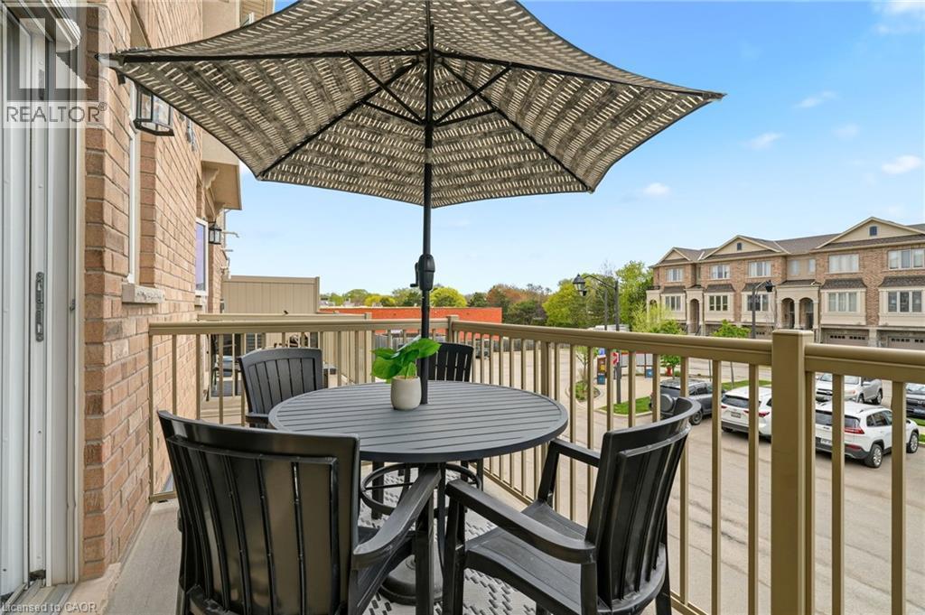 Balcony with a brick exterior, metal railing, and an exterior light fixture - 4171 Palermo Common, Burlington, ON - Outdoor With Exterior