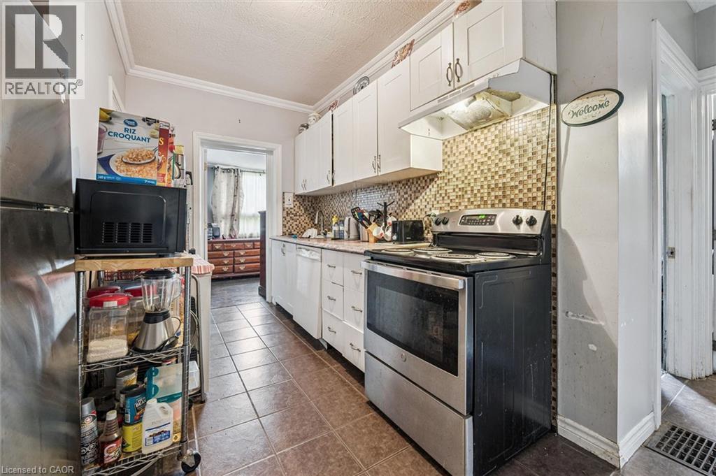 Stainless steel range and refrigerator, white cabinetry, tile flooring, and a mosaic tile backsplash - 27 Roseview Avenue, Cambridge, ON - Indoor Photo Showing Kitchen