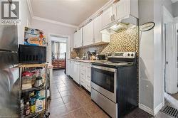 Stainless steel range and refrigerator, white cabinetry, tile flooring, and a mosaic tile backsplash -