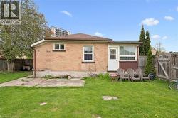 Brick ranch home with a spacious rear lawn featuring mature landscaping and established trees -
