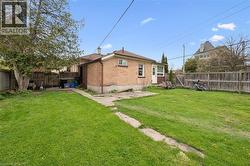 Spacious brick residence with a generous backyard featuring mature landscaping, manicured lawn, and wooden privacy fencing -
