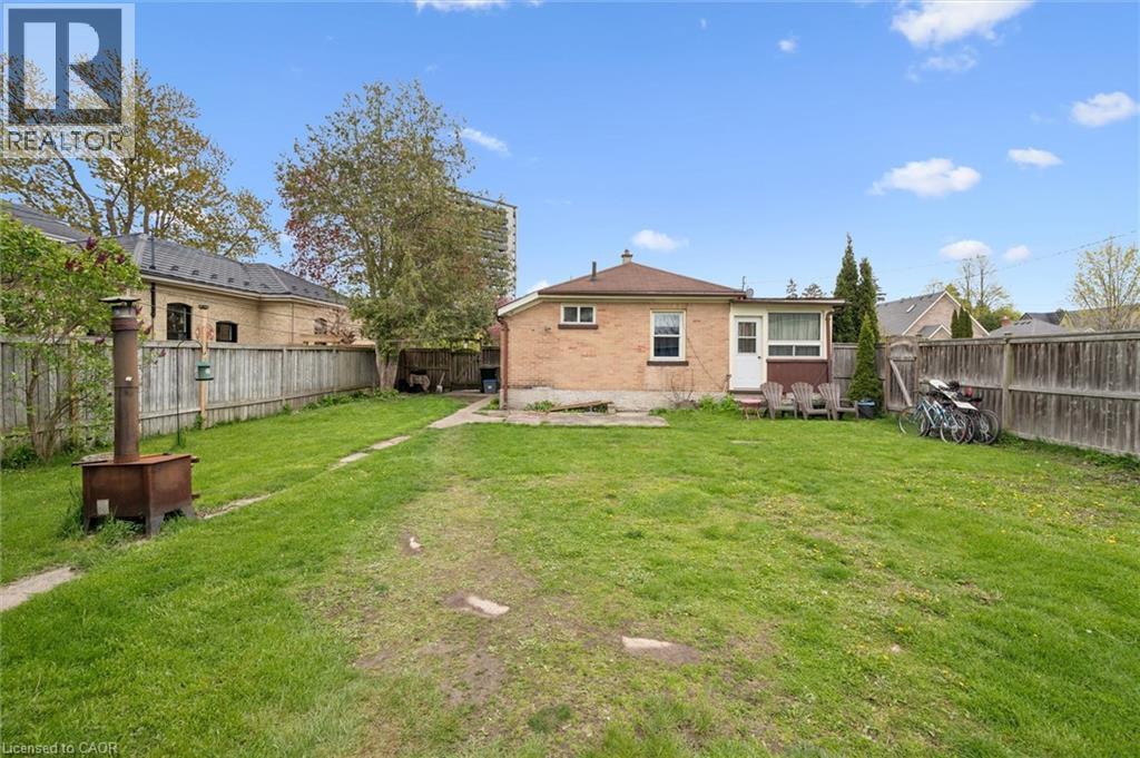 Expansive backyard featuring a manicured lawn, wood fencing, and a brick-clad exterior - 27 Roseview Avenue, Cambridge, ON - Outdoor With Backyard