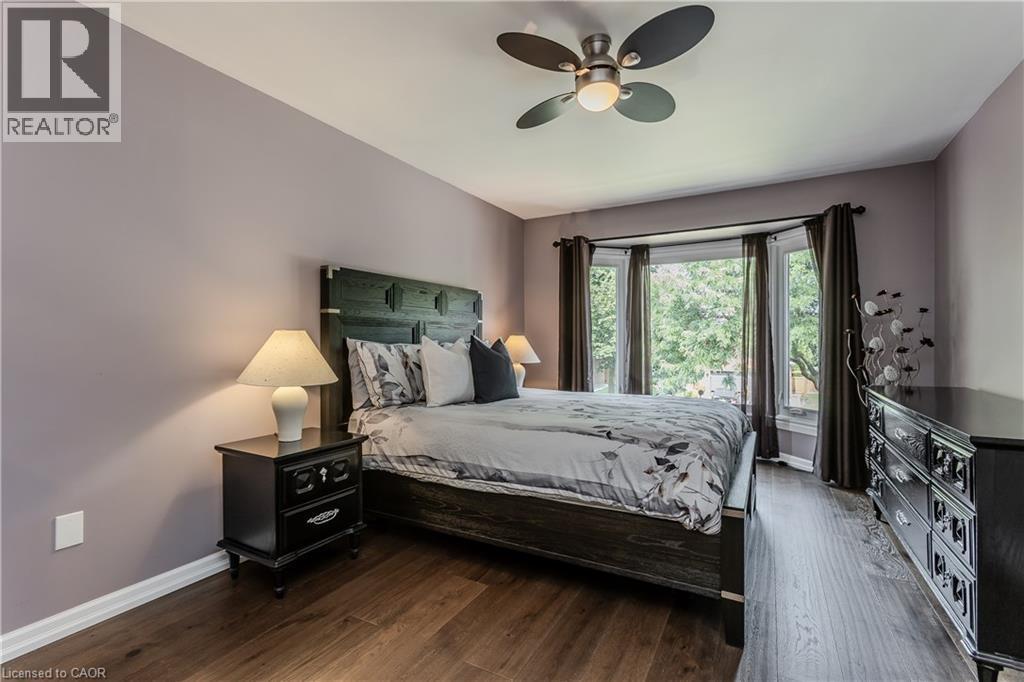 Bay window, wood-finish flooring, ceiling fan, and built-in headboard - 1238 Sable Drive, Burlington, ON - Indoor Photo Showing Bedroom