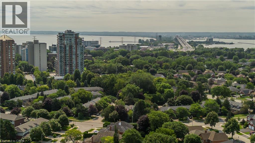 Aerial perspective of an urban landscape featuring diverse residential architecture, abundant mature trees, and a prominent body of water with a bridge structure - 1238 Sable Drive, Burlington, ON - Outdoor With Body Of Water With View